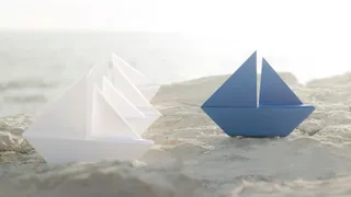 Four white origami boats and one blue, the leader