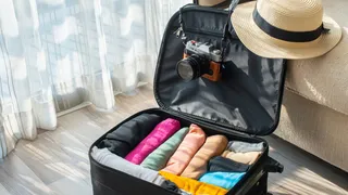 Open suitcase with hat and camera