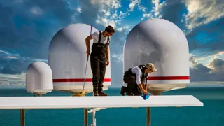 Two yacht crewmembers work to clean the yacht's exterior.
